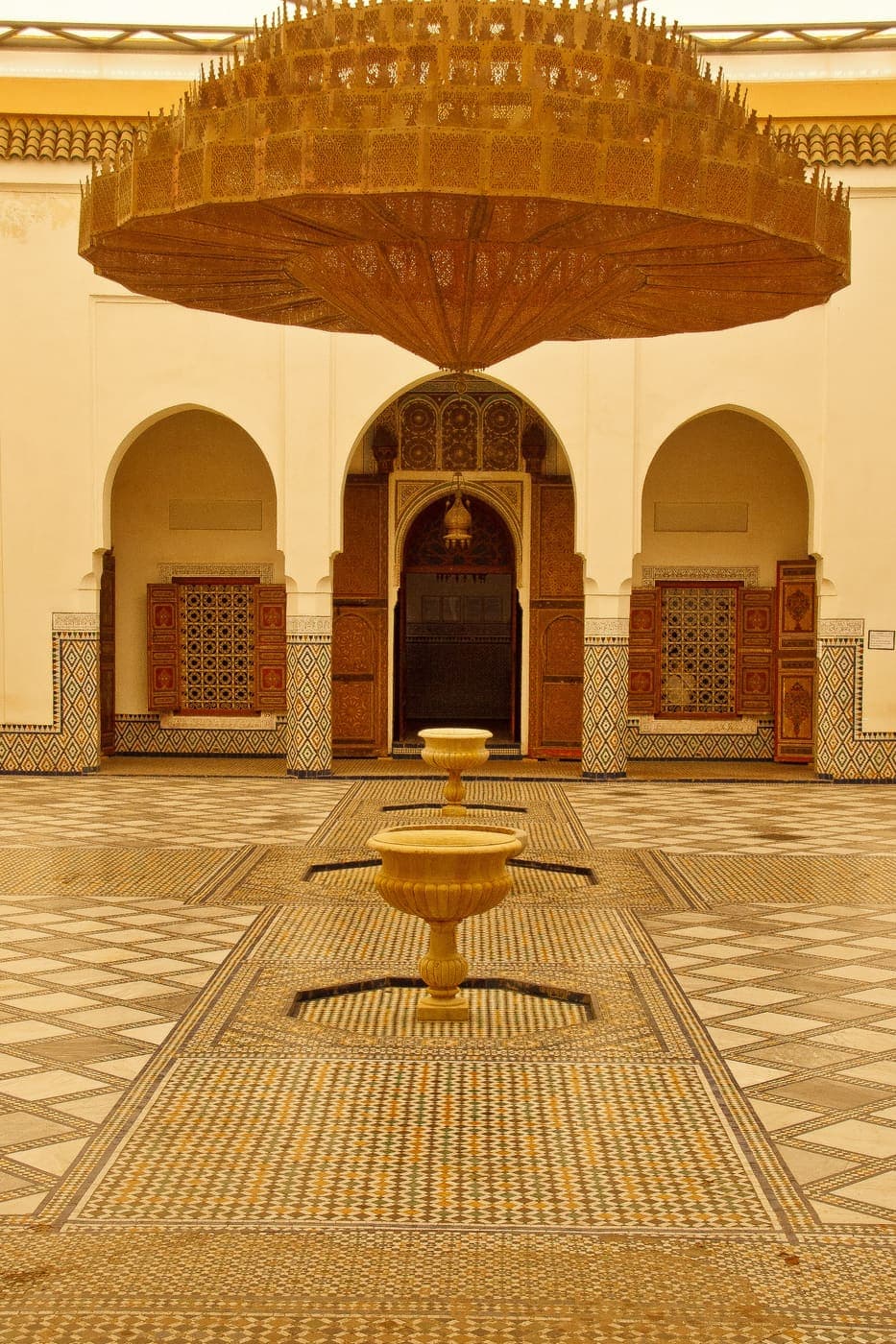 Patio d’un riad marocain avec arches, lustre et fontaine